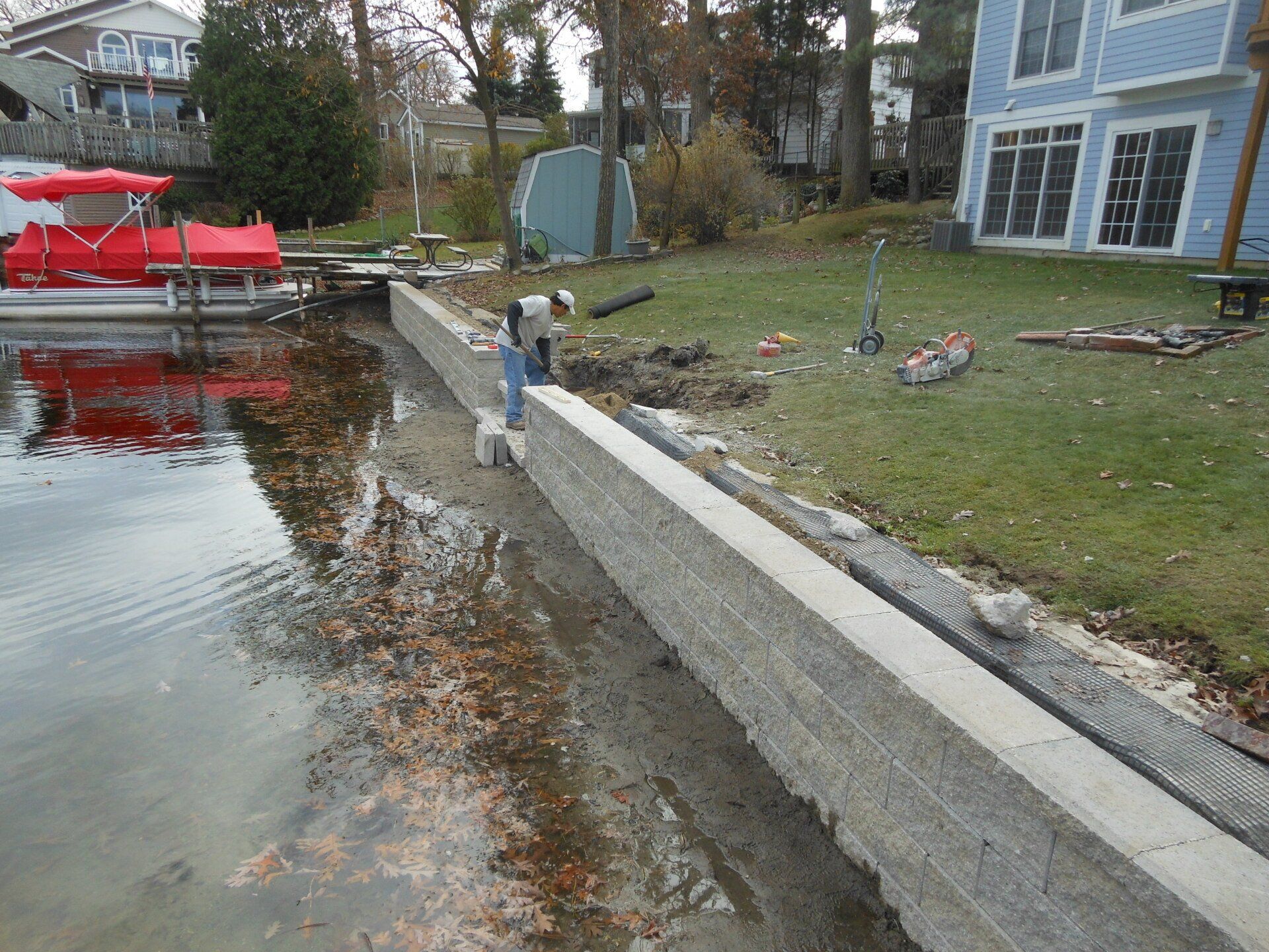 A man is working on a concrete wall next to a body of water.