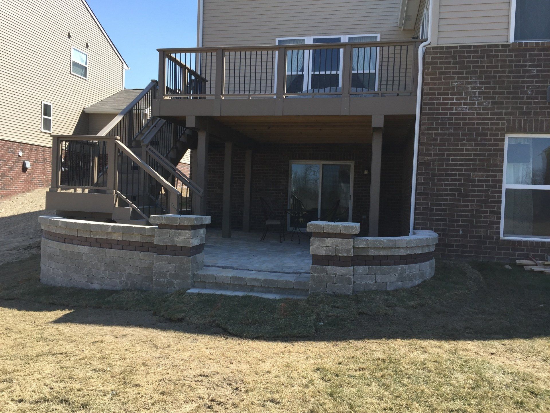 A deck with stairs leading up to it is in the backyard of a house.