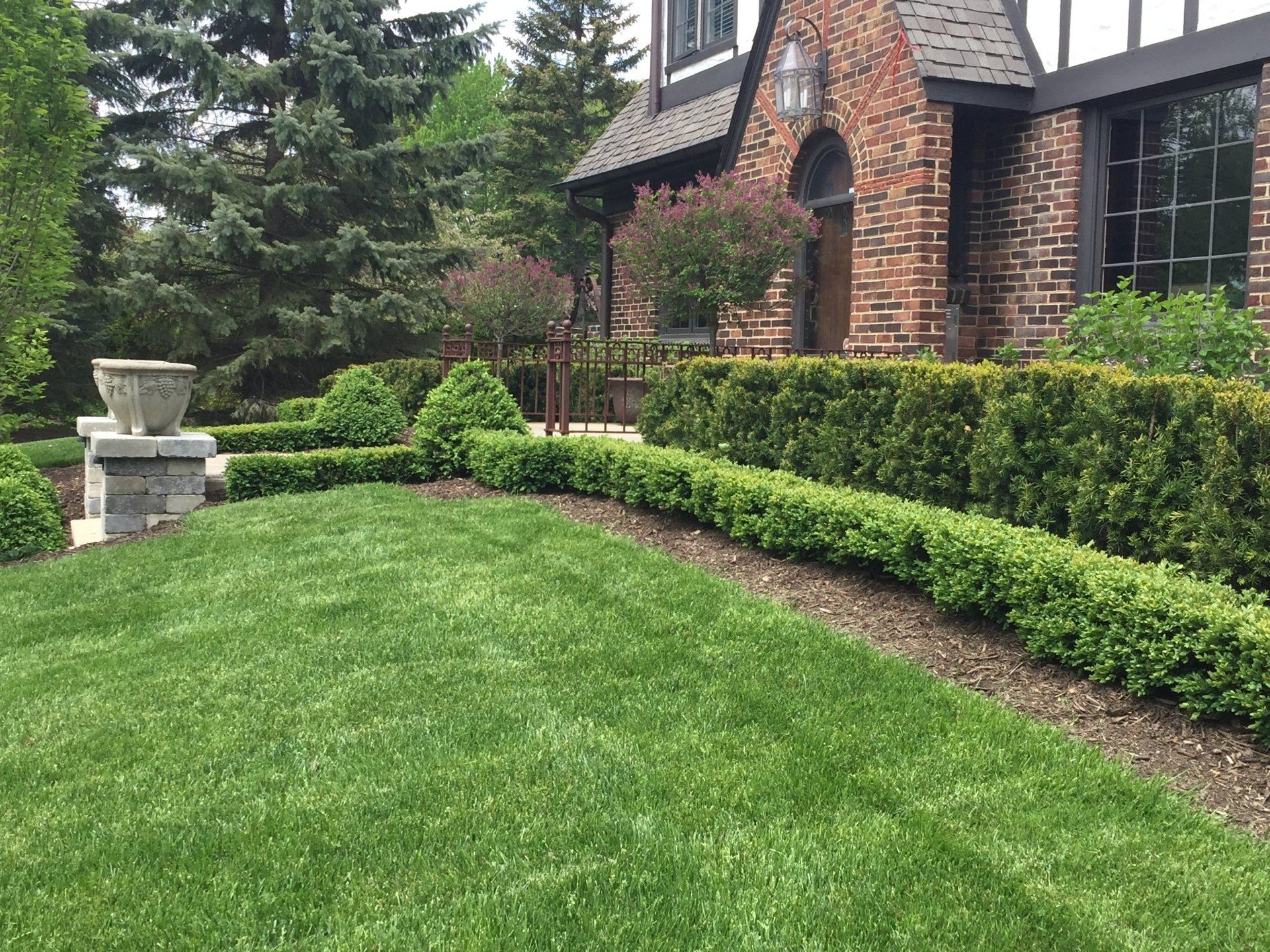 A large brick house with a lush green lawn in front of it.
