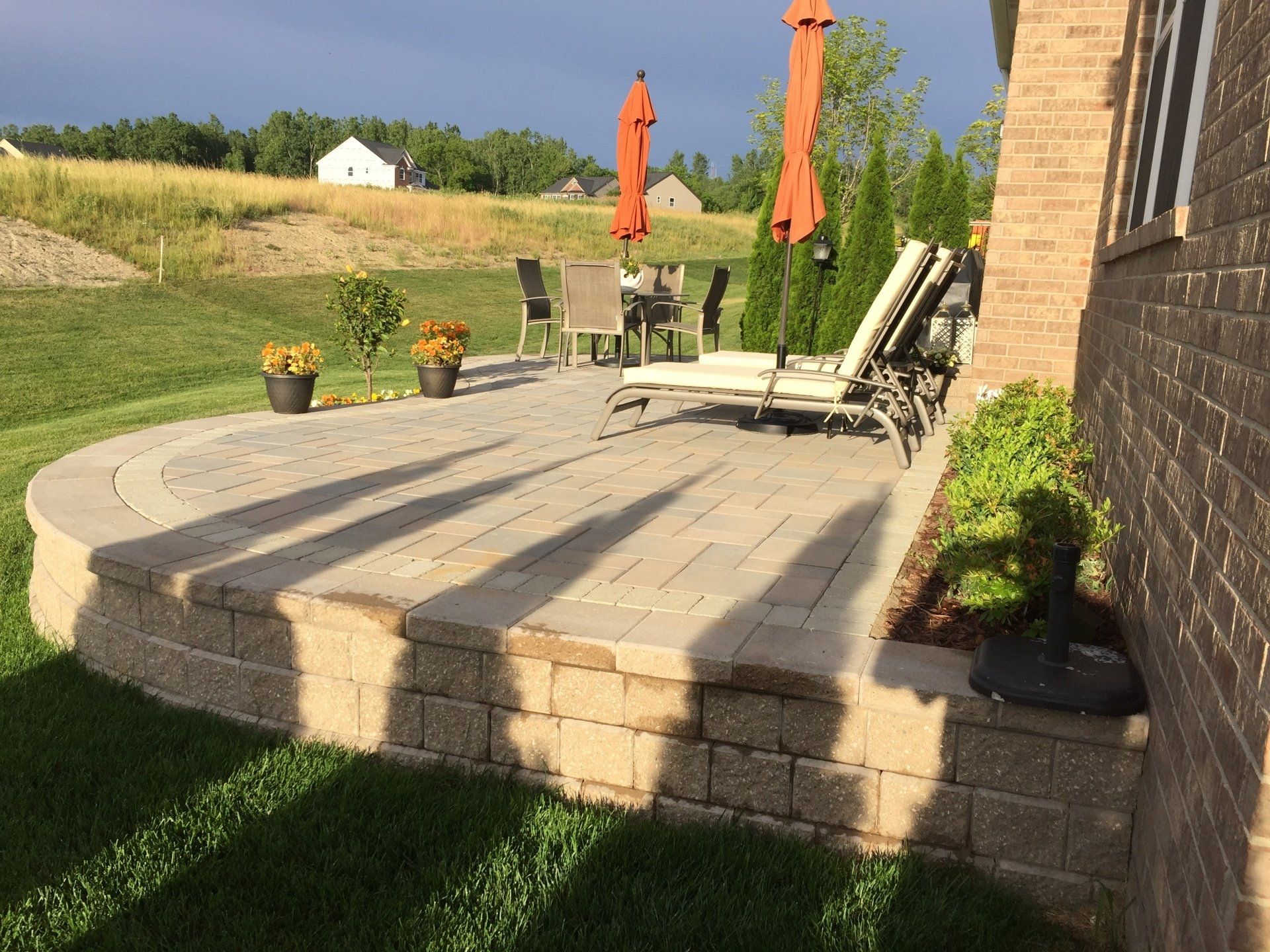 A patio with chairs and umbrellas in the backyard of a house.