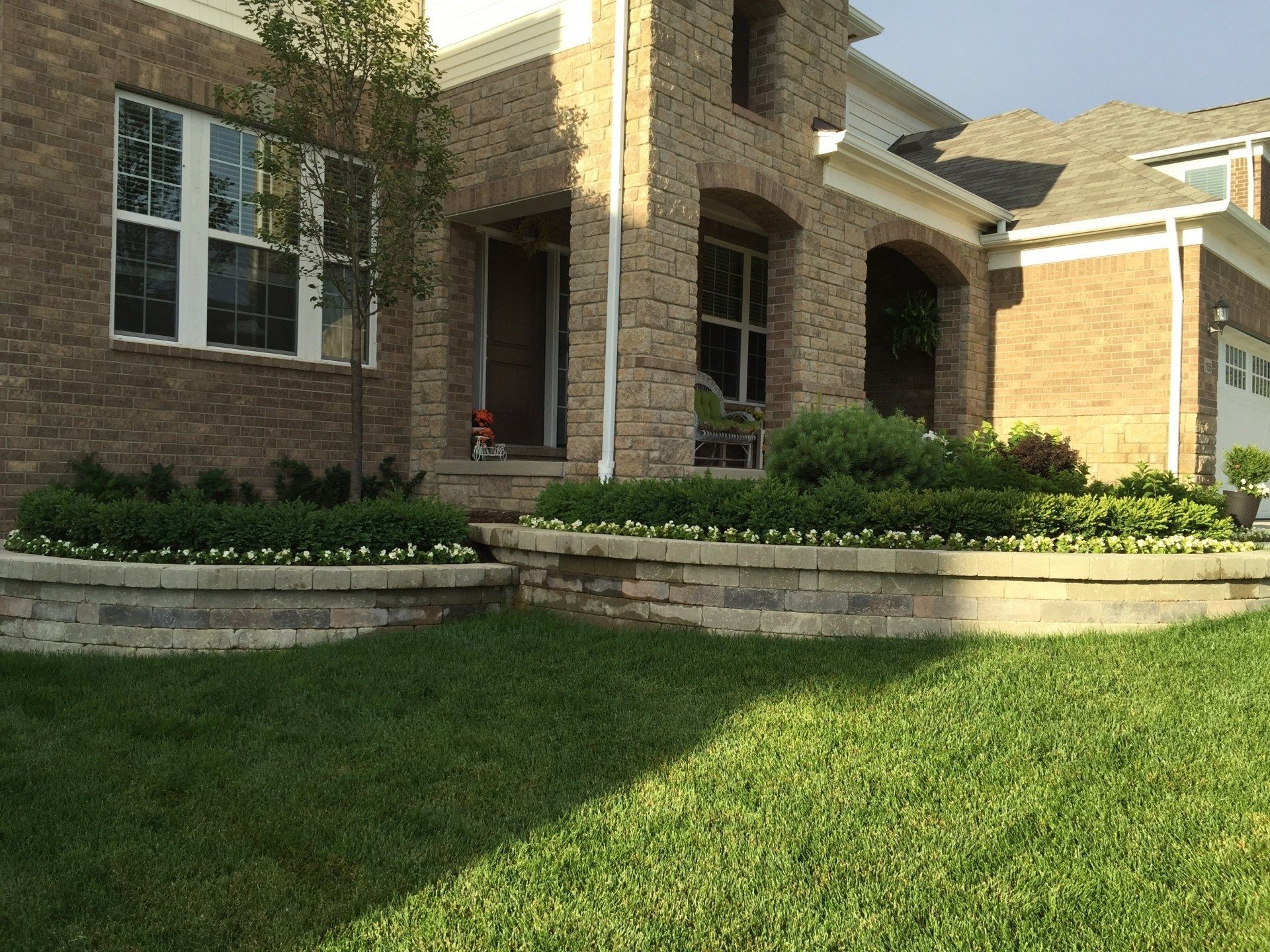 A brick house with a lush green lawn in front of it