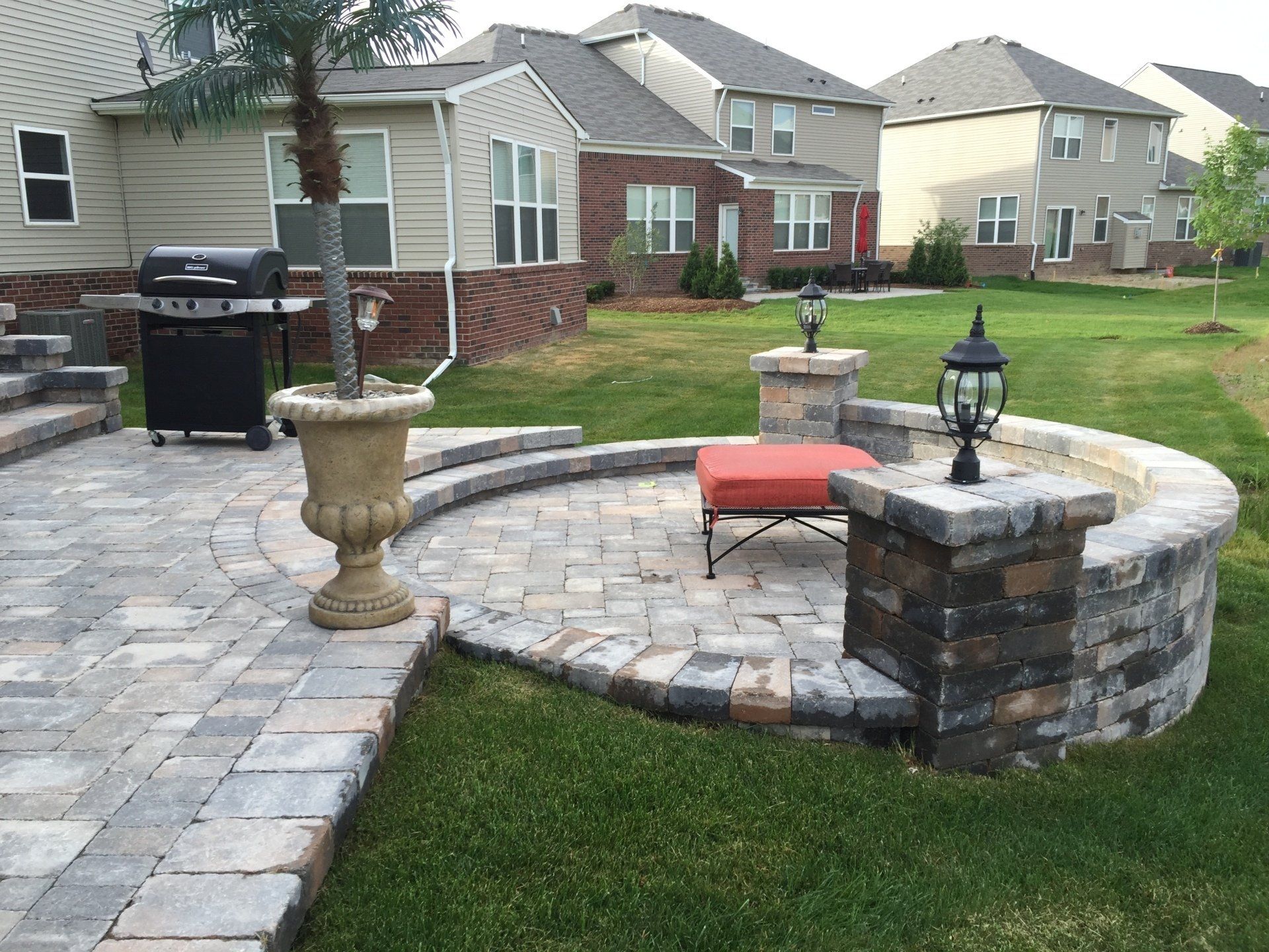 A patio with a fire pit and a grill in the backyard