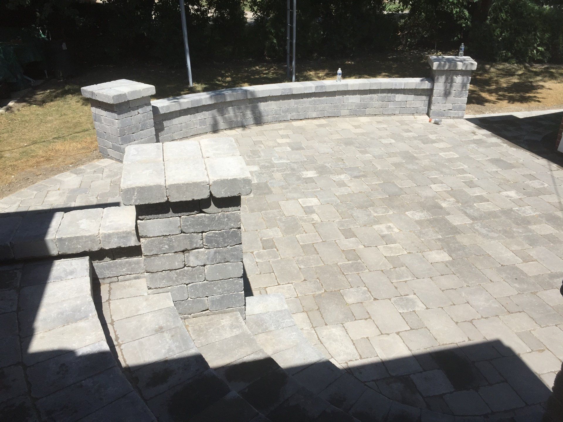 A brick patio with steps and a stone wall