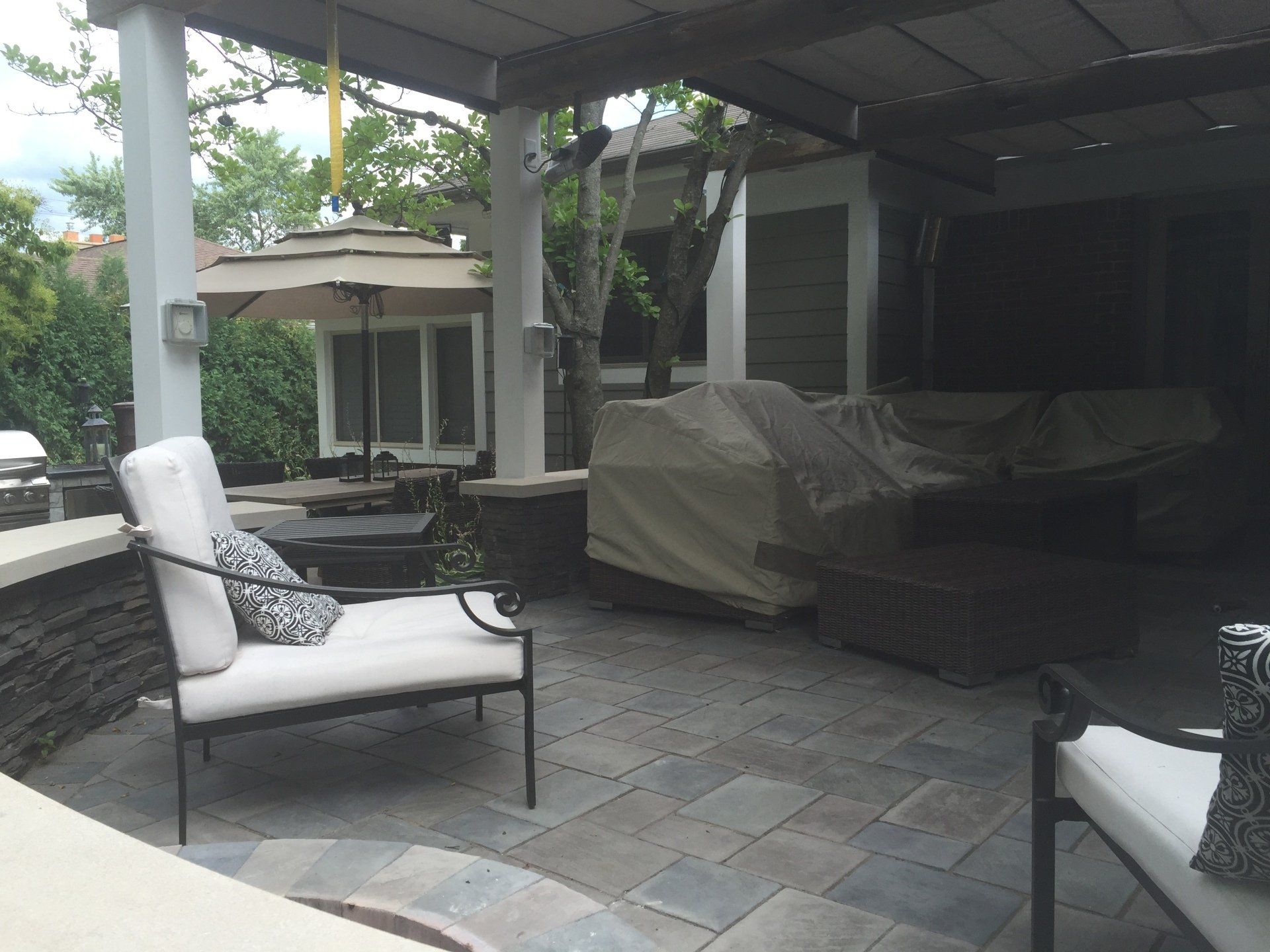 A patio with chairs and umbrellas in front of a house