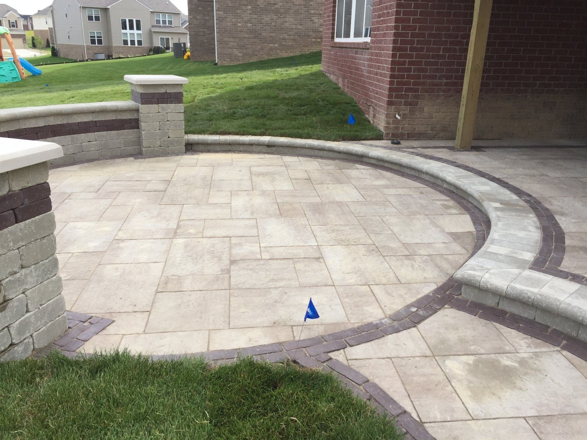 A circular patio with a brick wall and a brick building in the background.