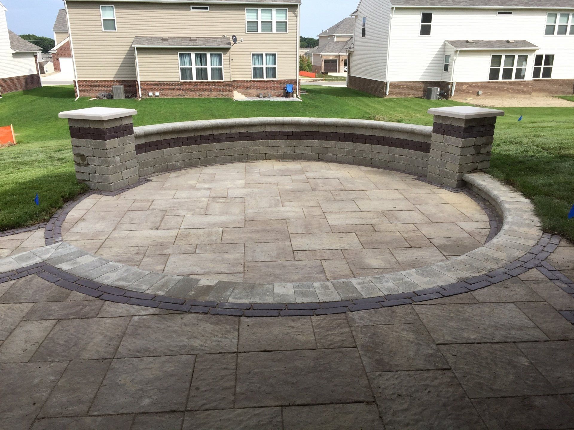A circular patio with a brick wall surrounding it in front of a house.