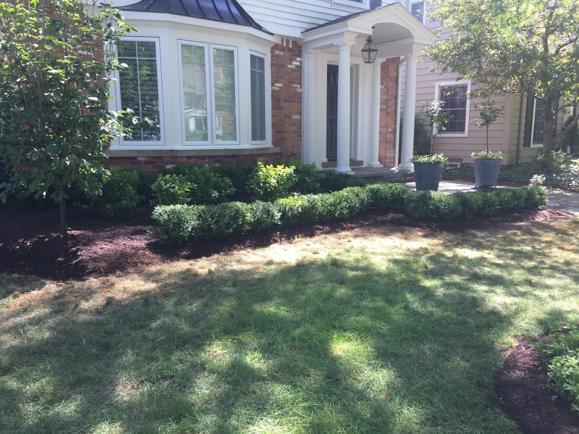 A house with a lush green lawn and bushes in front of it.