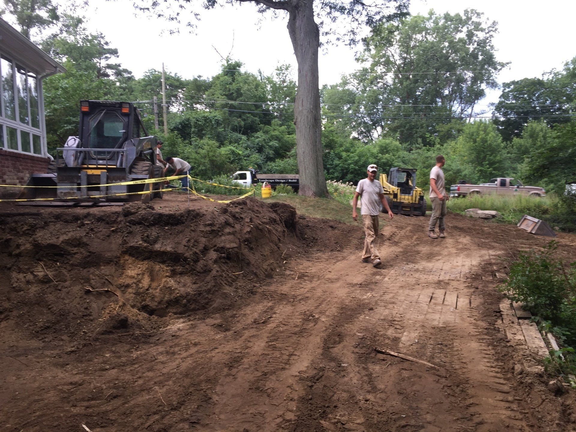A man is walking down a dirt road in front of a bulldozer.
