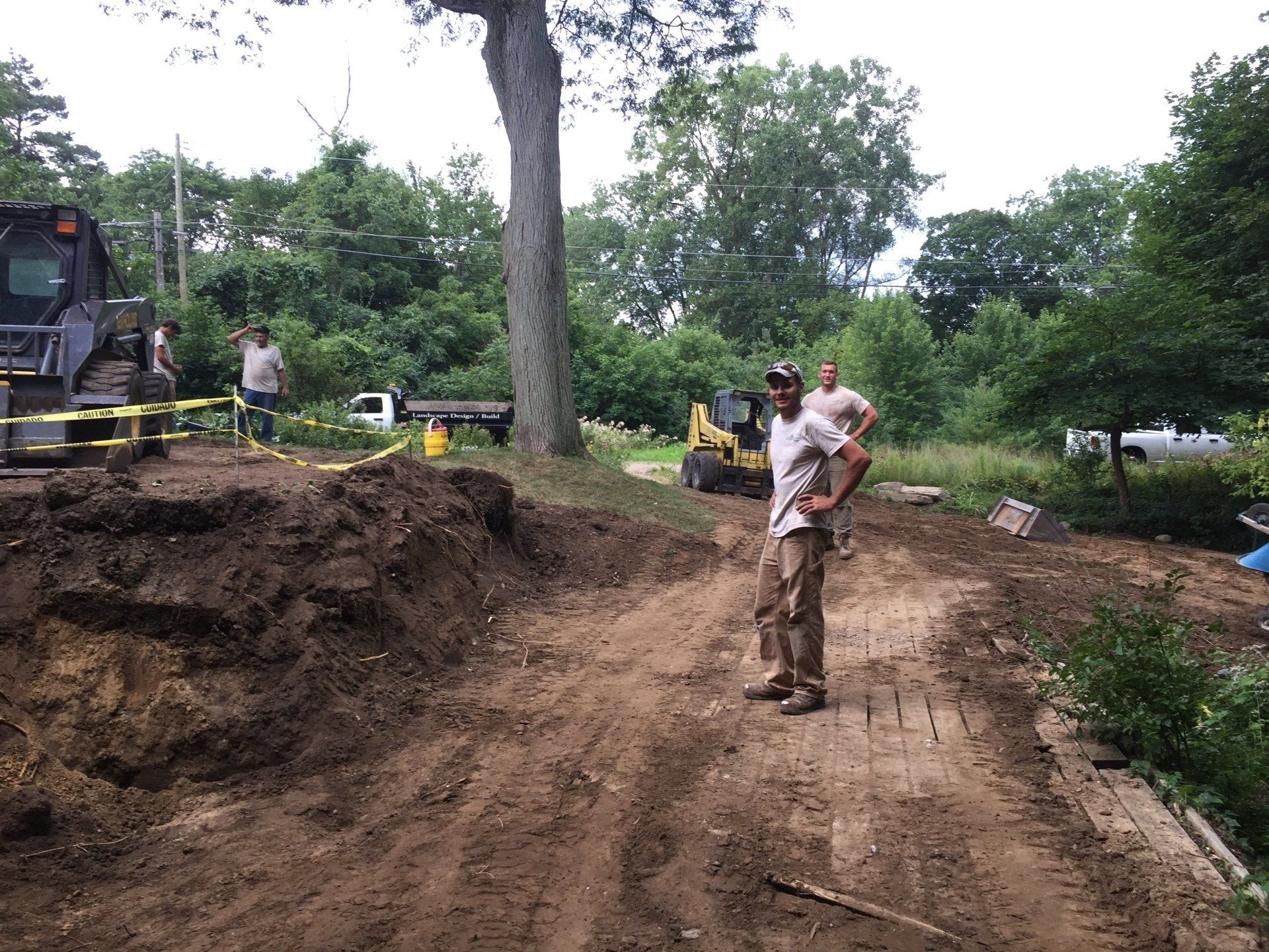 A man is standing on a dirt road in front of a bulldozer.