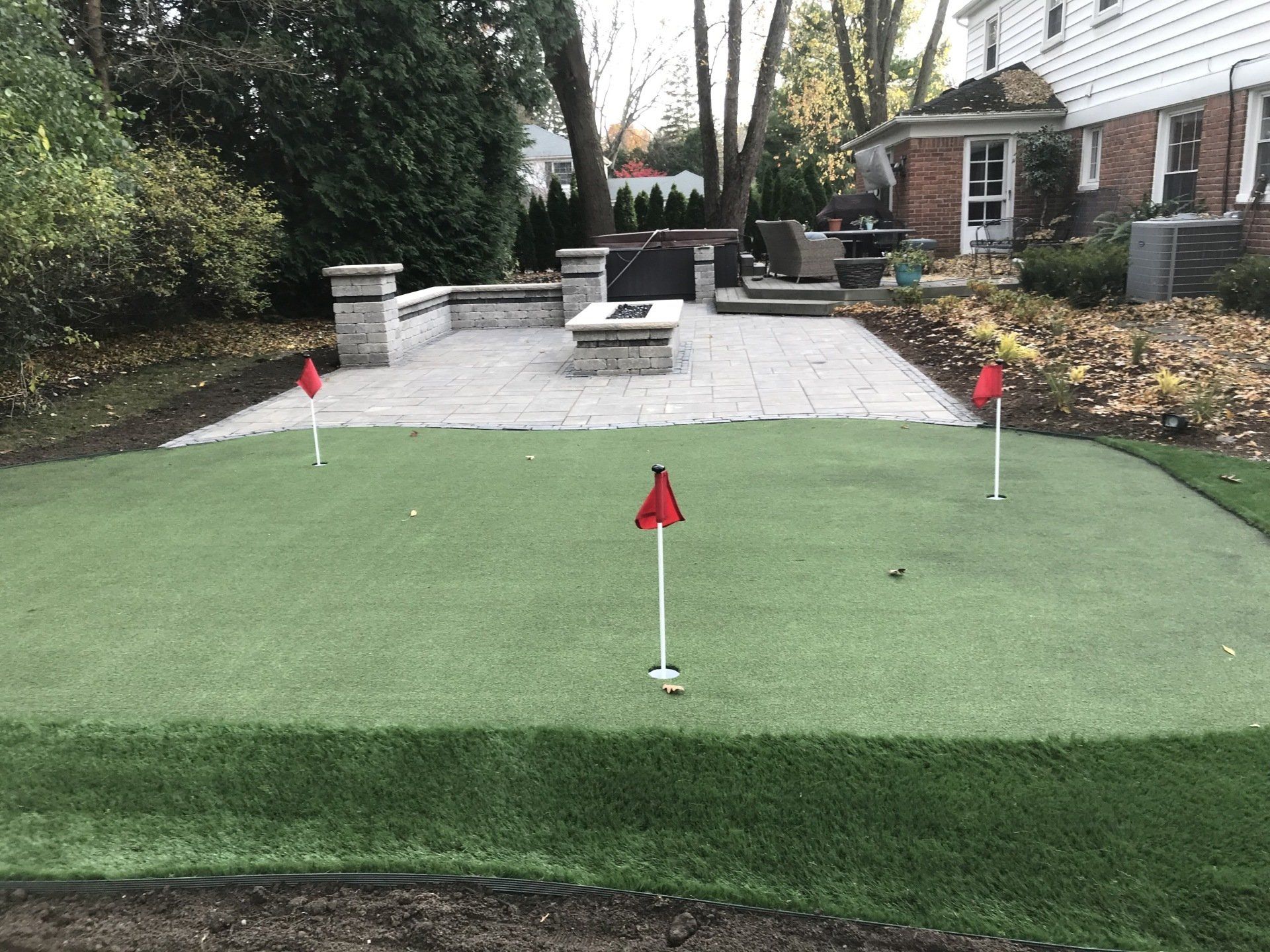 There is a putting green in the backyard of a house.