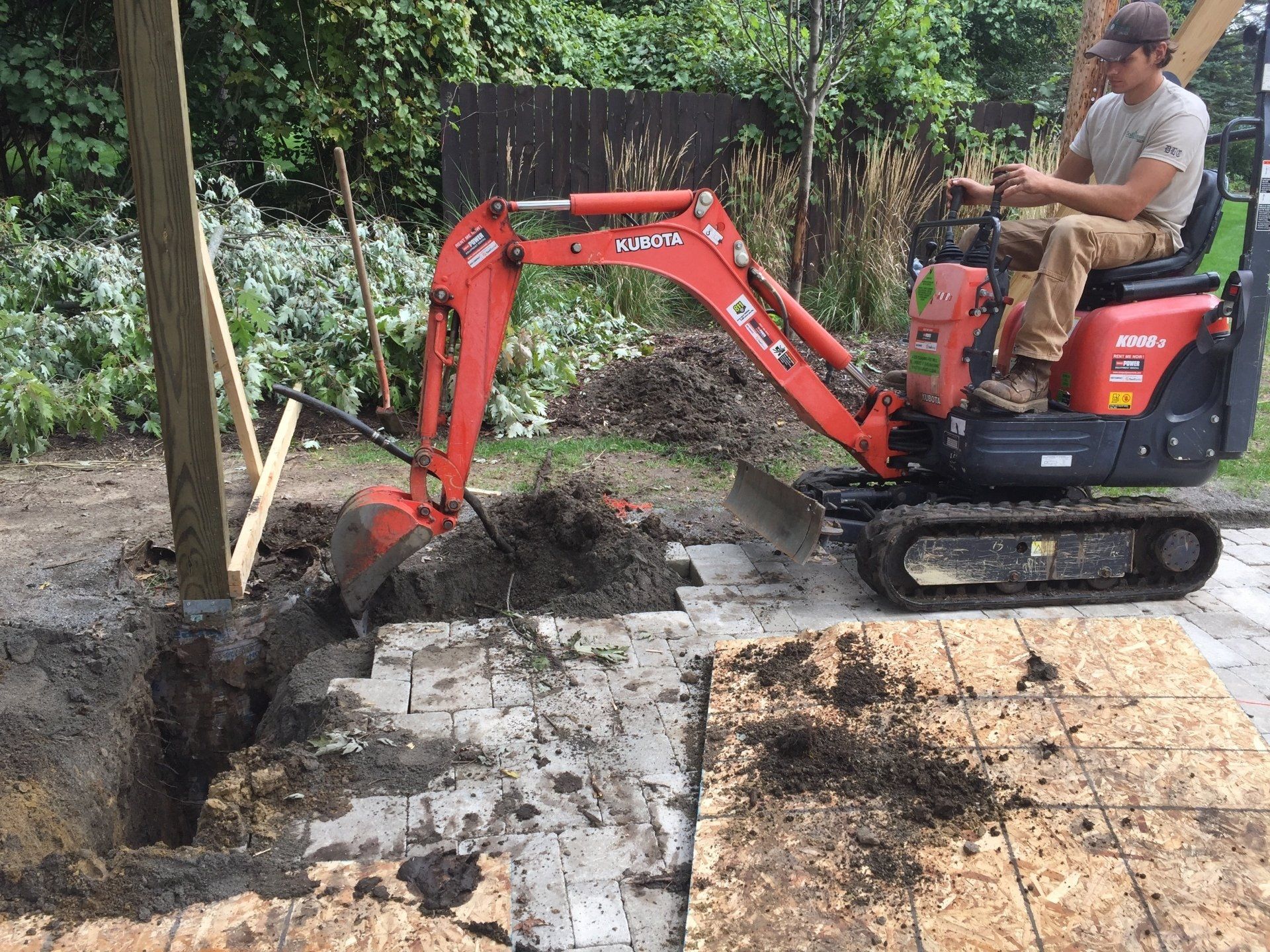 A man is sitting on a small excavator digging a hole in the ground.