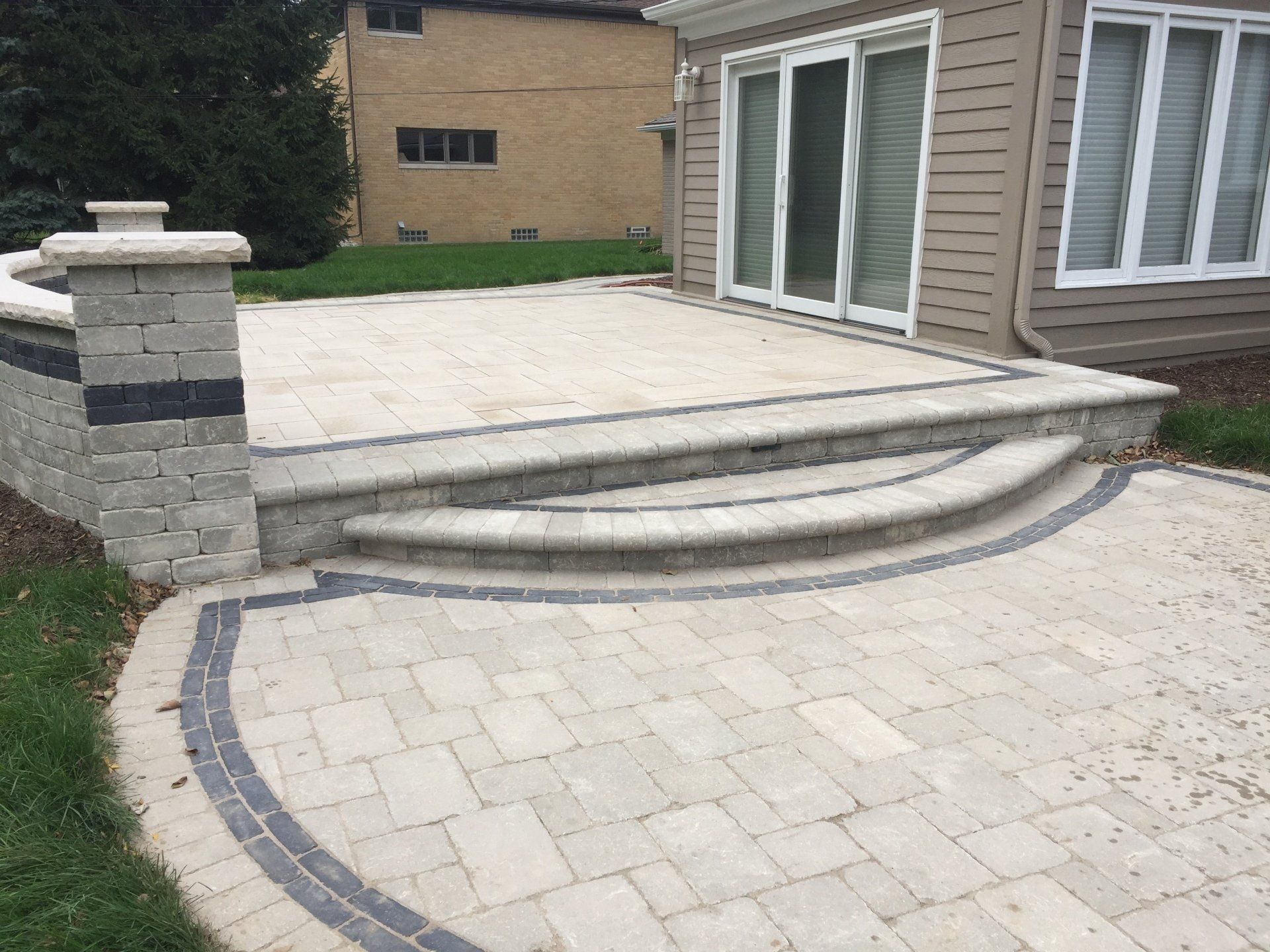 A patio with steps leading to a house with sliding glass doors.