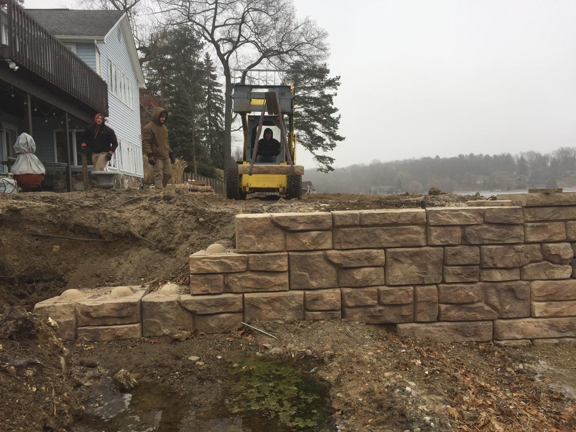 A forklift is moving a brick wall in front of a house