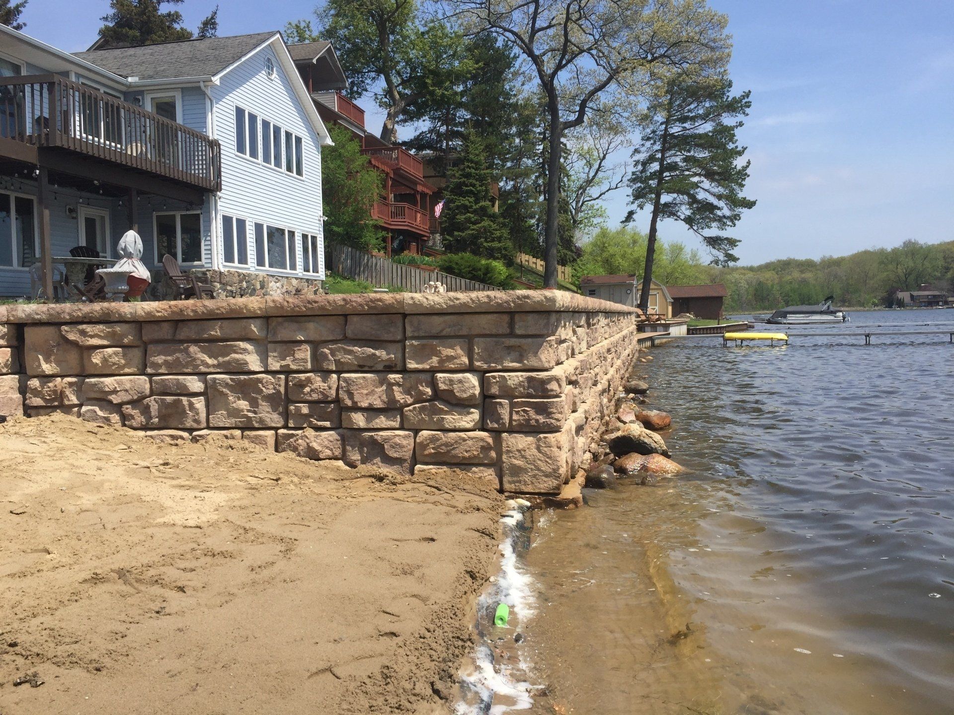 A house is sitting on the shore of a lake next to a brick wall.