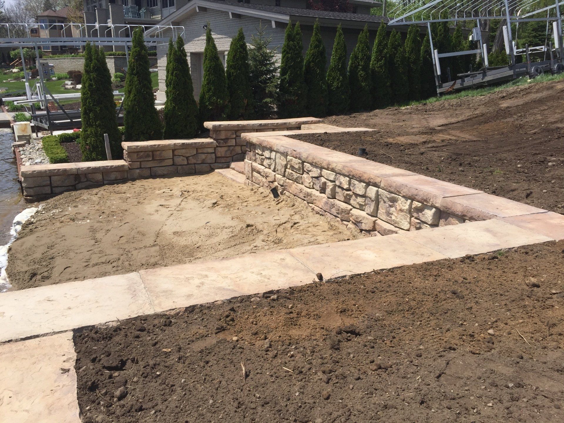 A stone wall is being built in the middle of a dirt field.