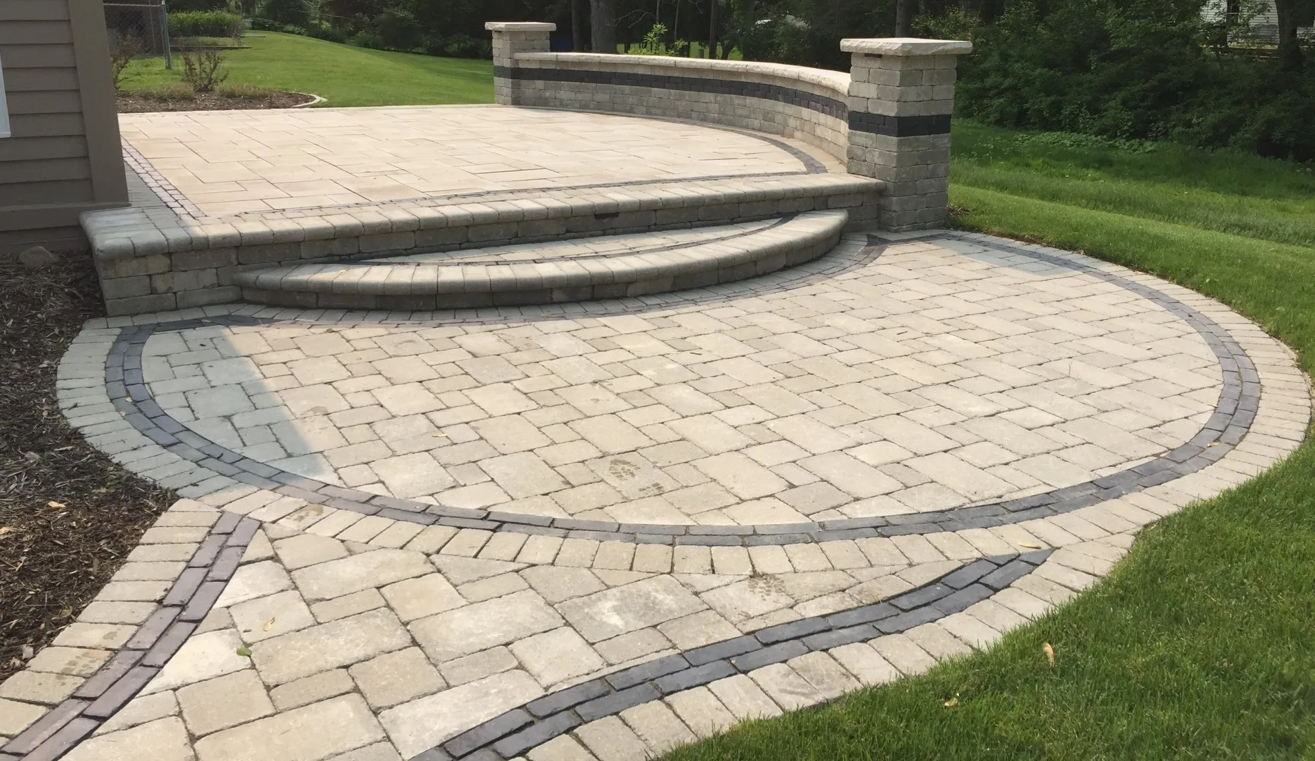 A brick patio with steps and a wall in the backyard.