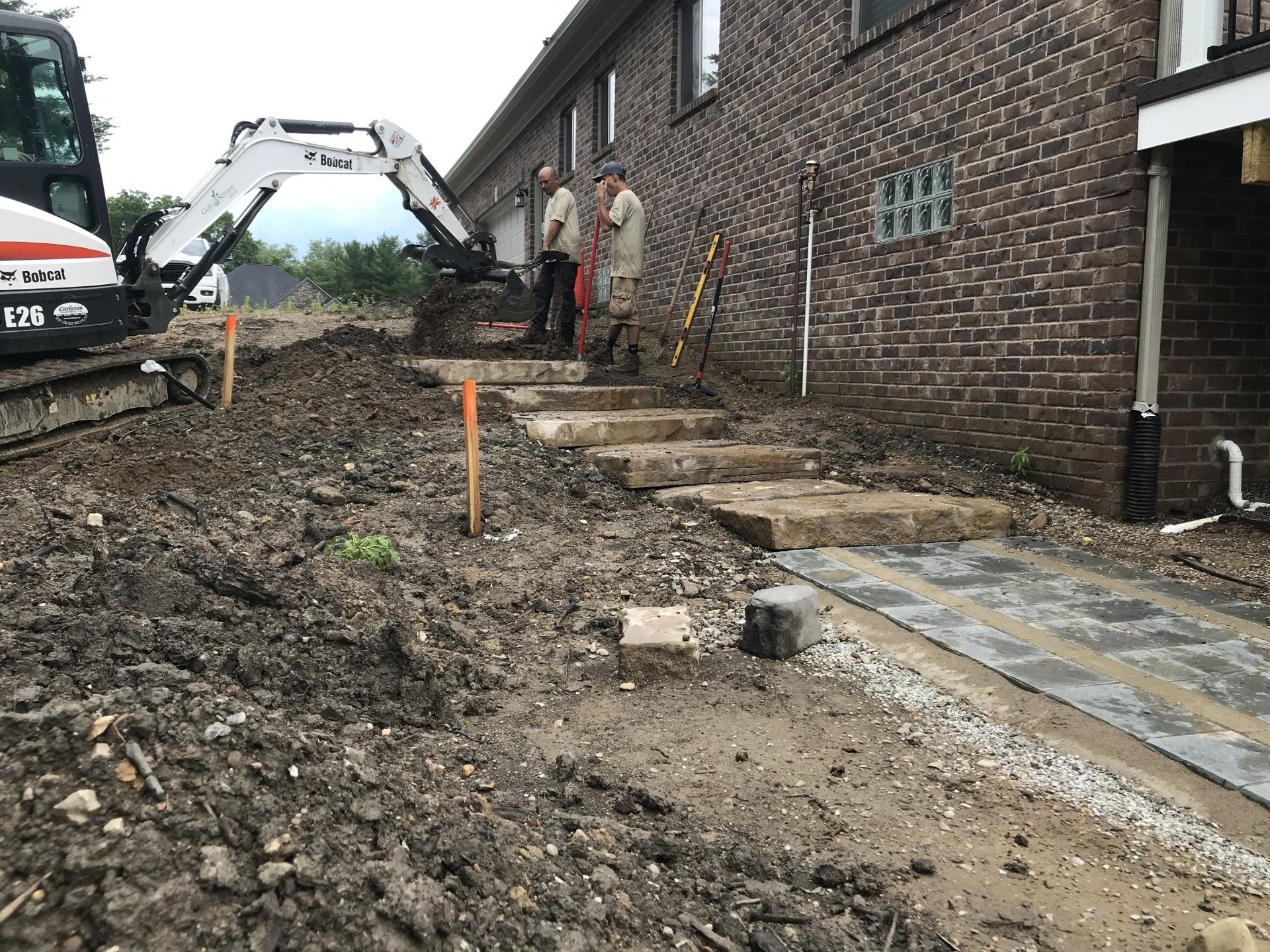 A man is standing next to a bulldozer in front of a brick building.