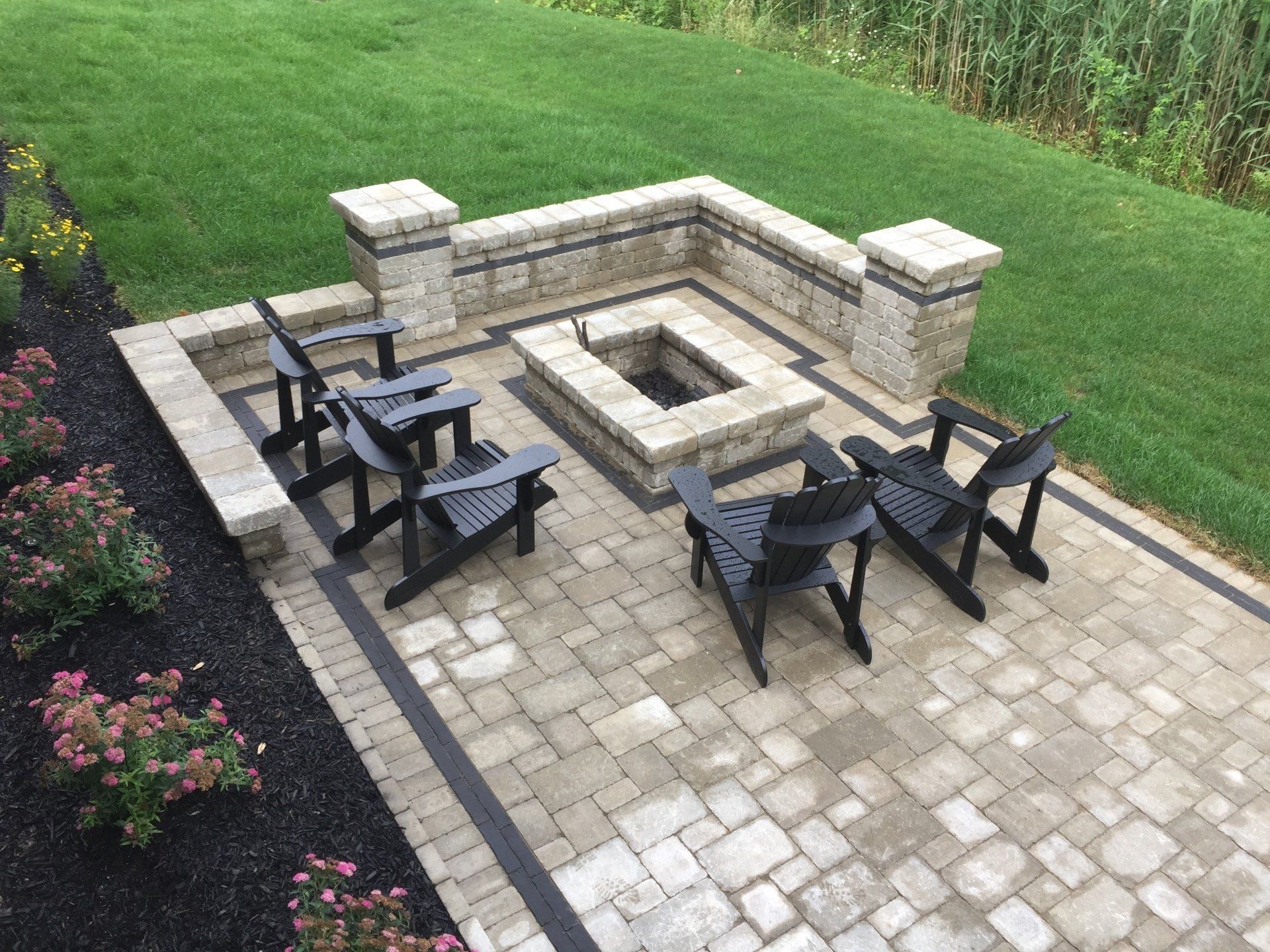 A patio with a fire pit and chairs on it.