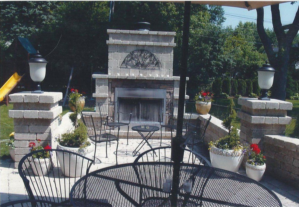 A patio with a table and chairs and a fireplace