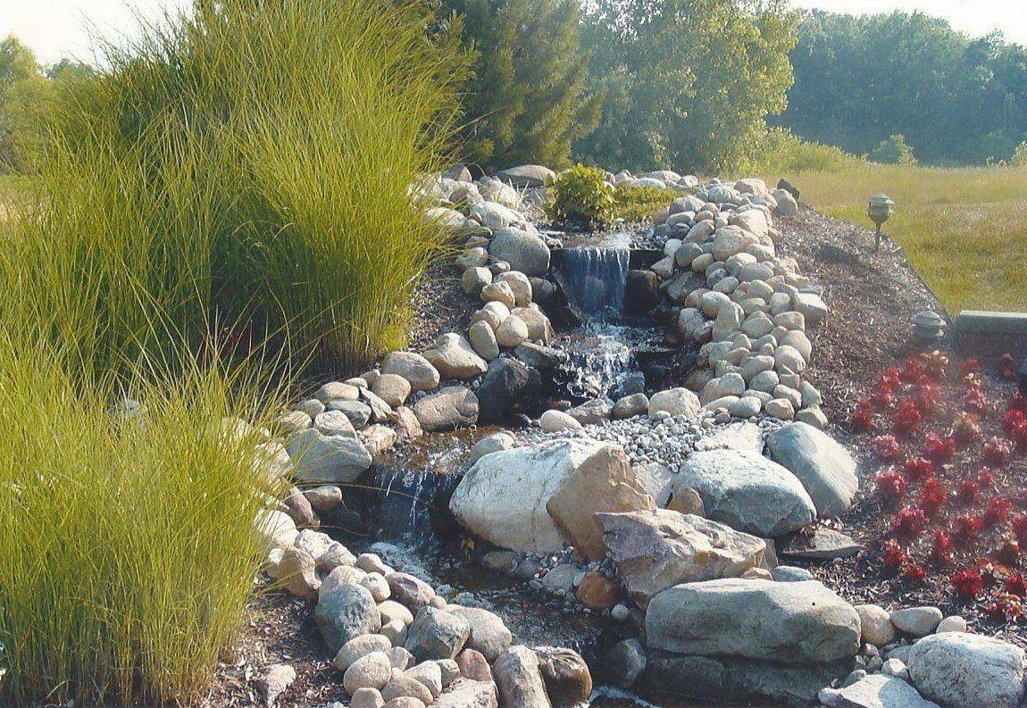 A small waterfall is surrounded by rocks and trees