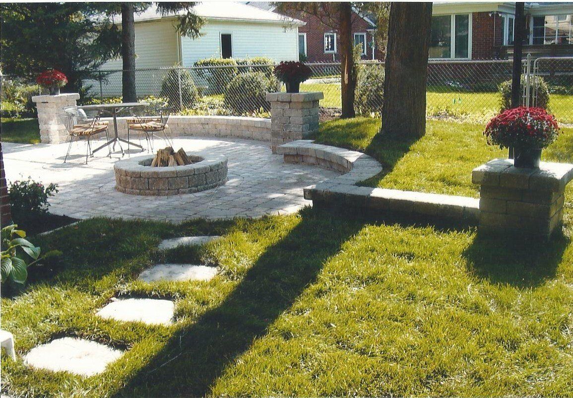 A fire pit sits in the middle of a lush green yard