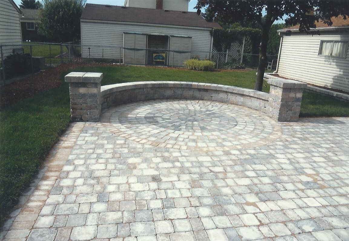 A brick patio with a circular design in the middle