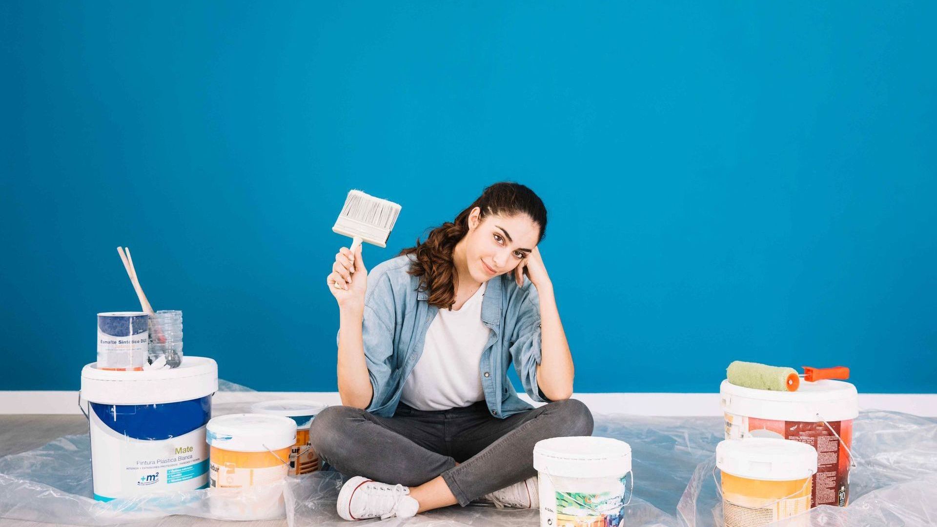 woman sitting in front of paint cans looking confused