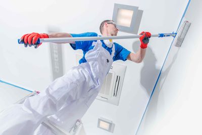 painter using roller to paint interior wall