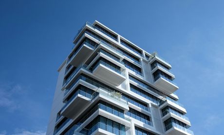 A tall building with a lot of balconies against a blue sky.