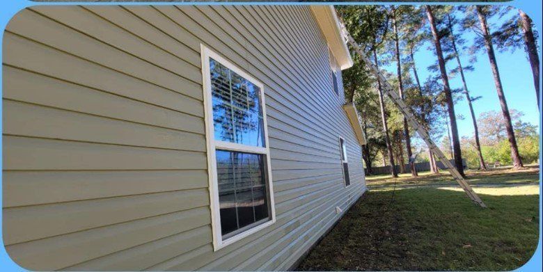 The side of a house with a window and trees in the background.