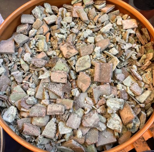 Frammenti di roccia marrone e verde in un secchio arancione.