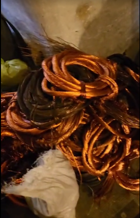 Fili di rame arrotolati, alcuni con isolamento nero, accatastati insieme.