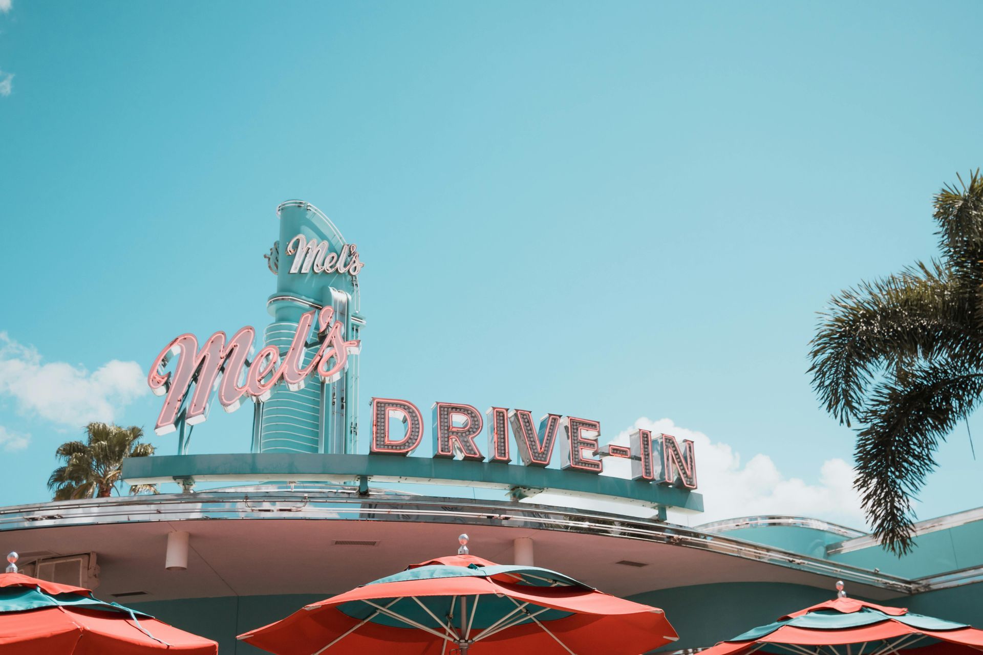 A drive-in restaurant with umbrellas in front of it.