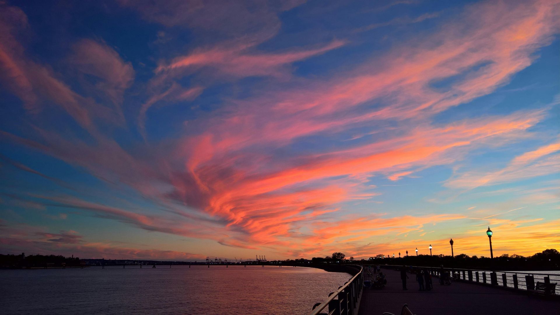 A sunset over a body of water with a pier in the foreground