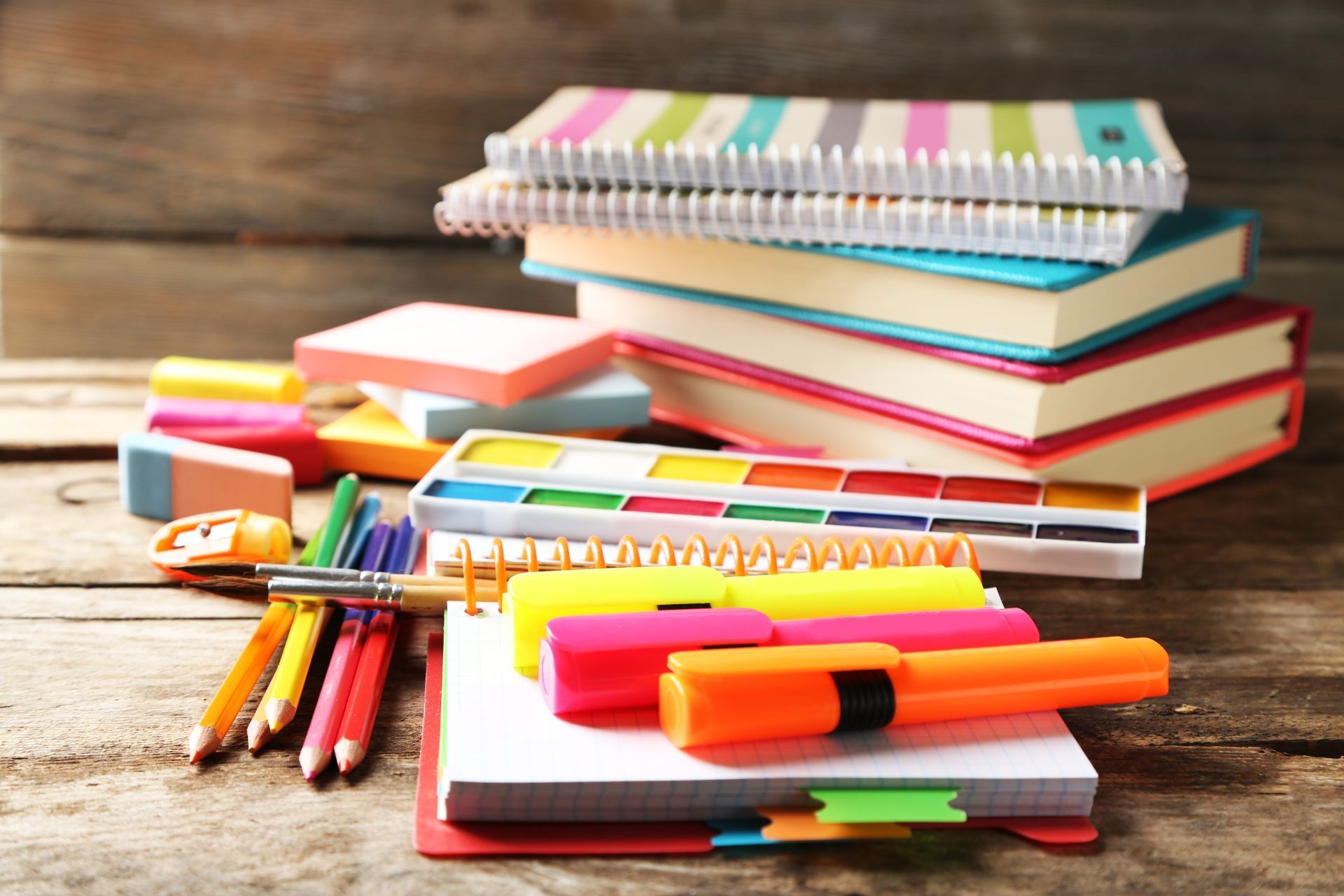 A stack of books and school supplies on a wooden table