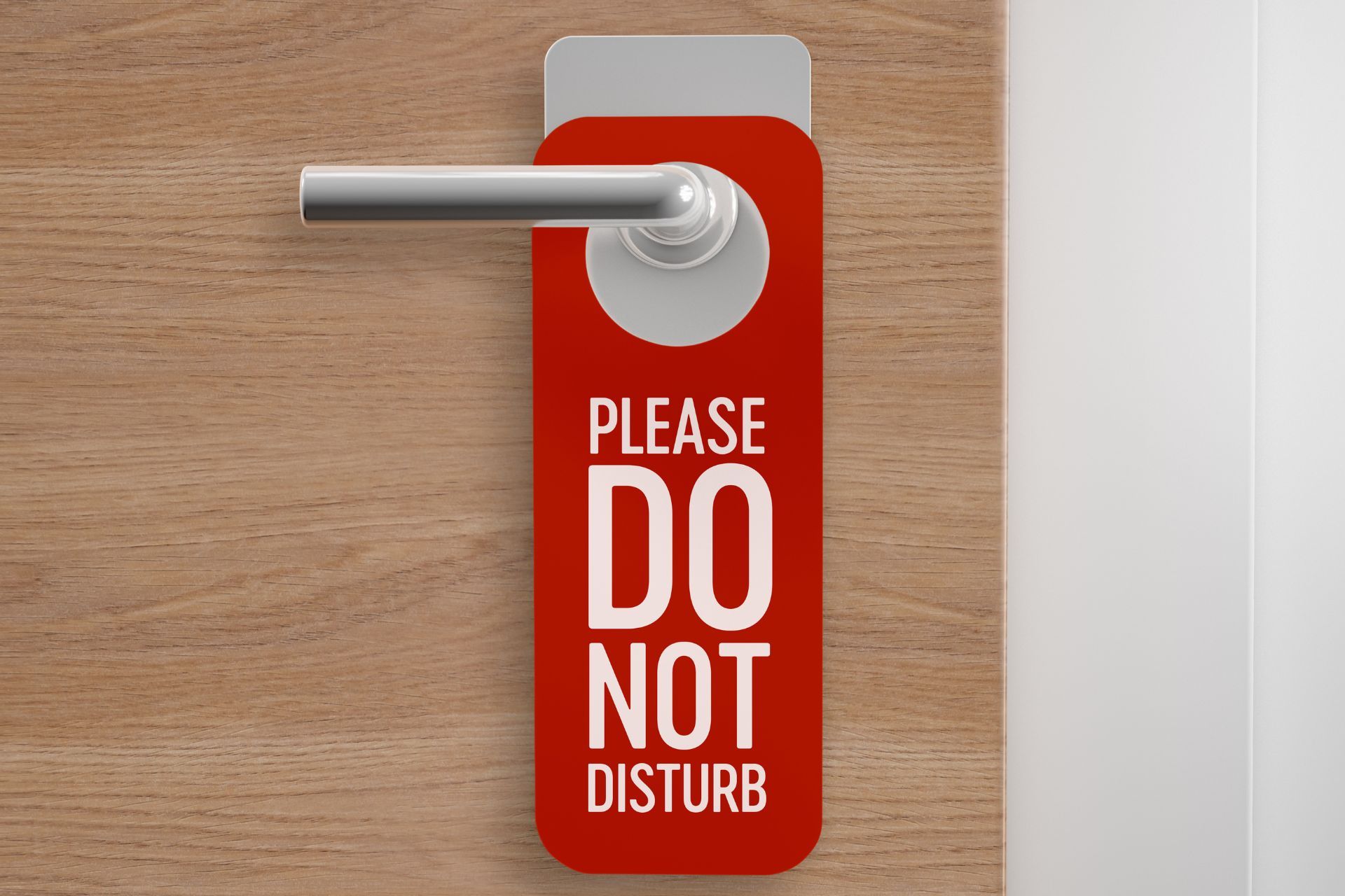 A red do not disturb sign hangs on a wooden door.