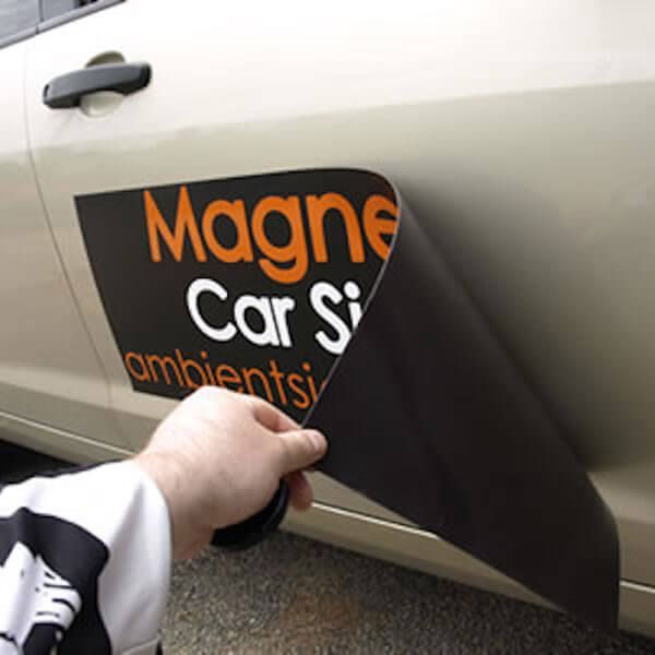 A person is putting a magnet on the side of a car