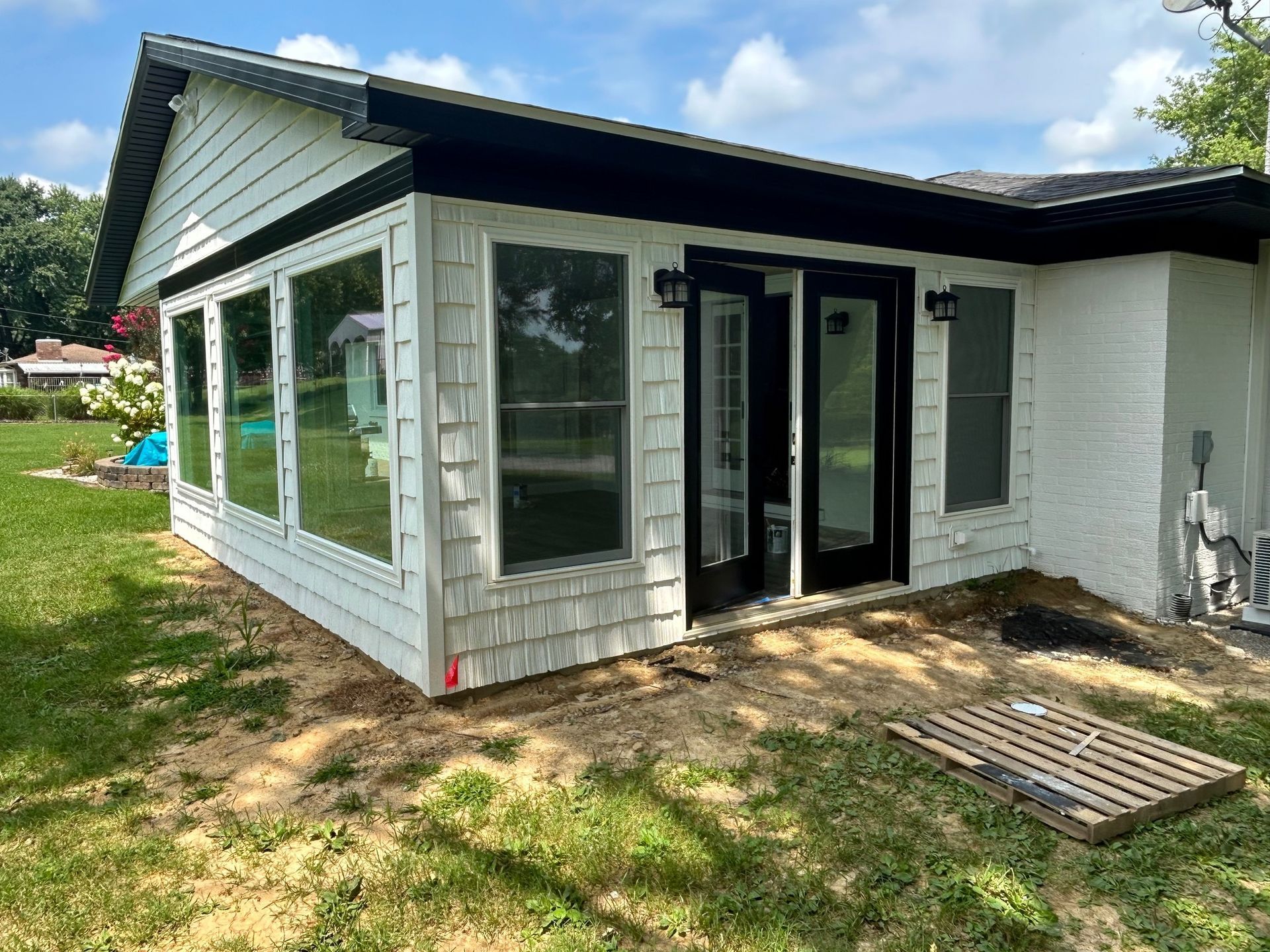 A man on a ladder paints the side of a house