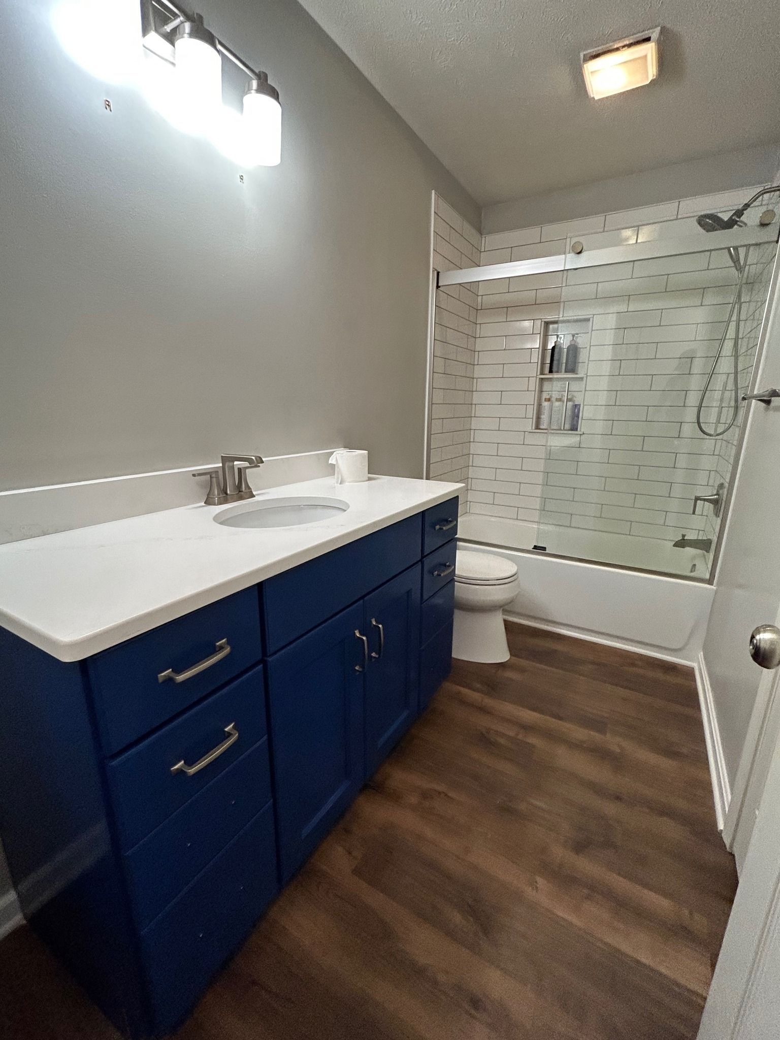 A person is painting a white cabinet door with a brush.
