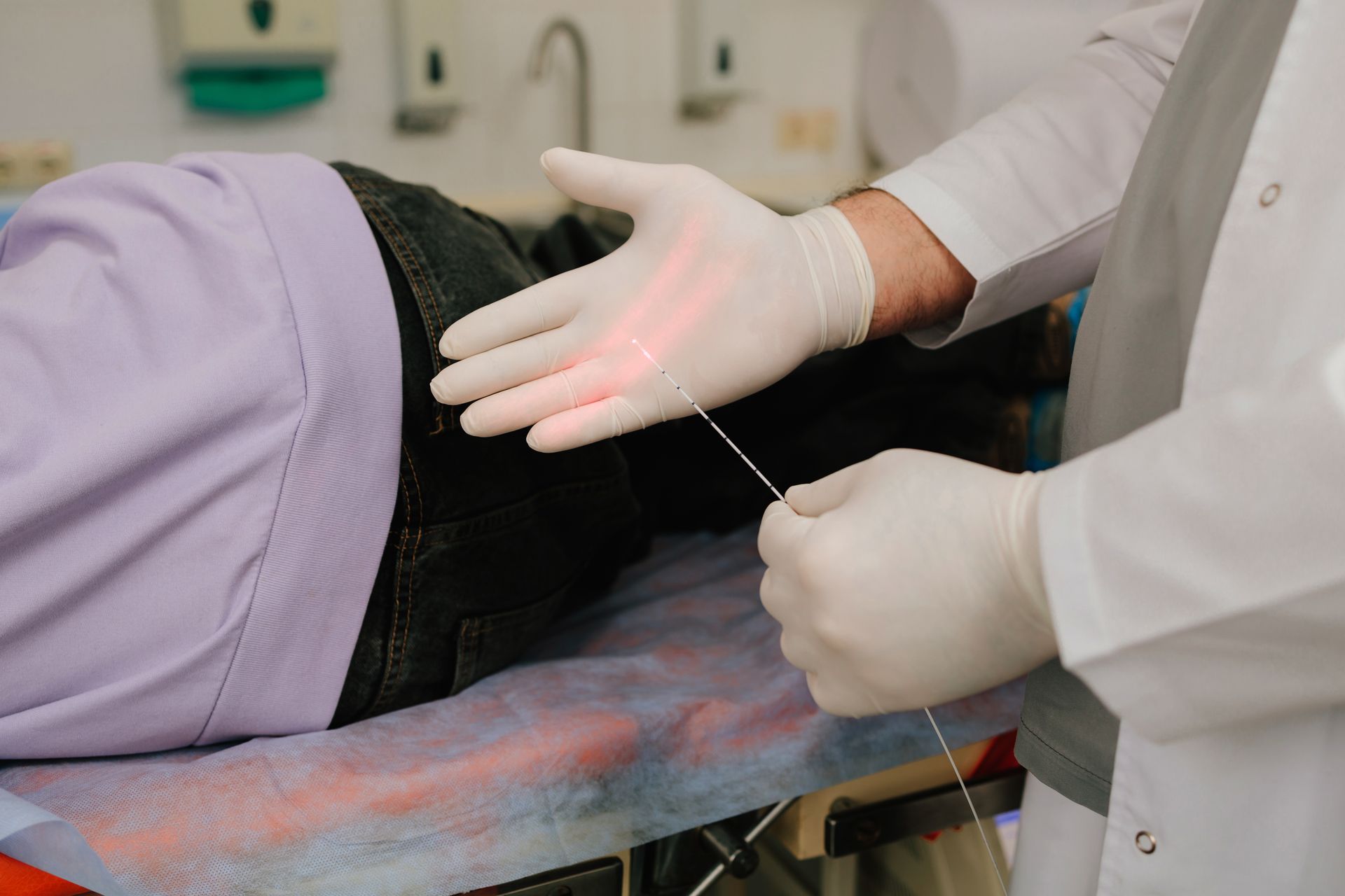 Medical professional inserting a needle into a patient’s lower back during a procedure