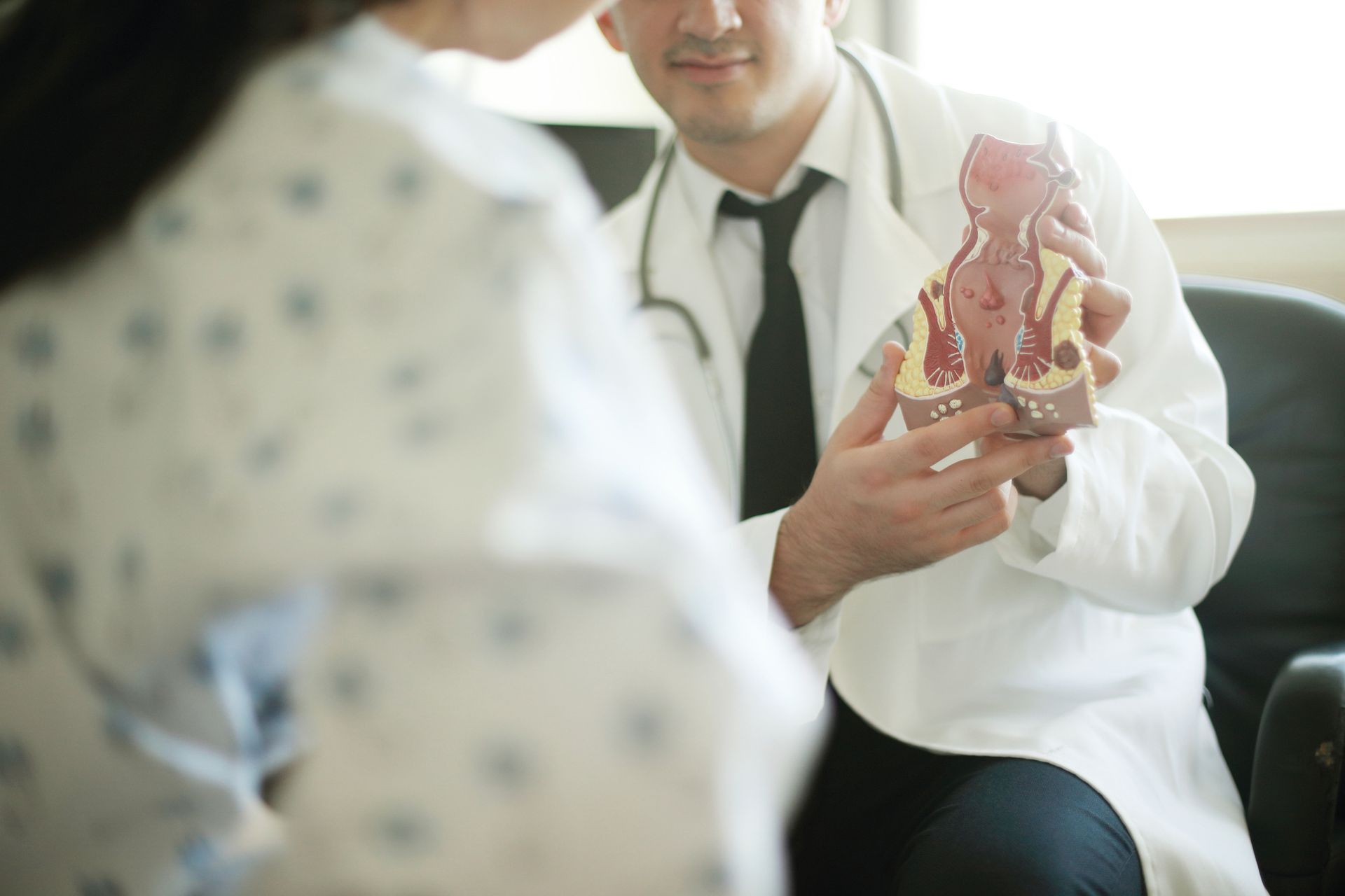A rectal specialist discusses treatment options with a woman during a patient consultation.