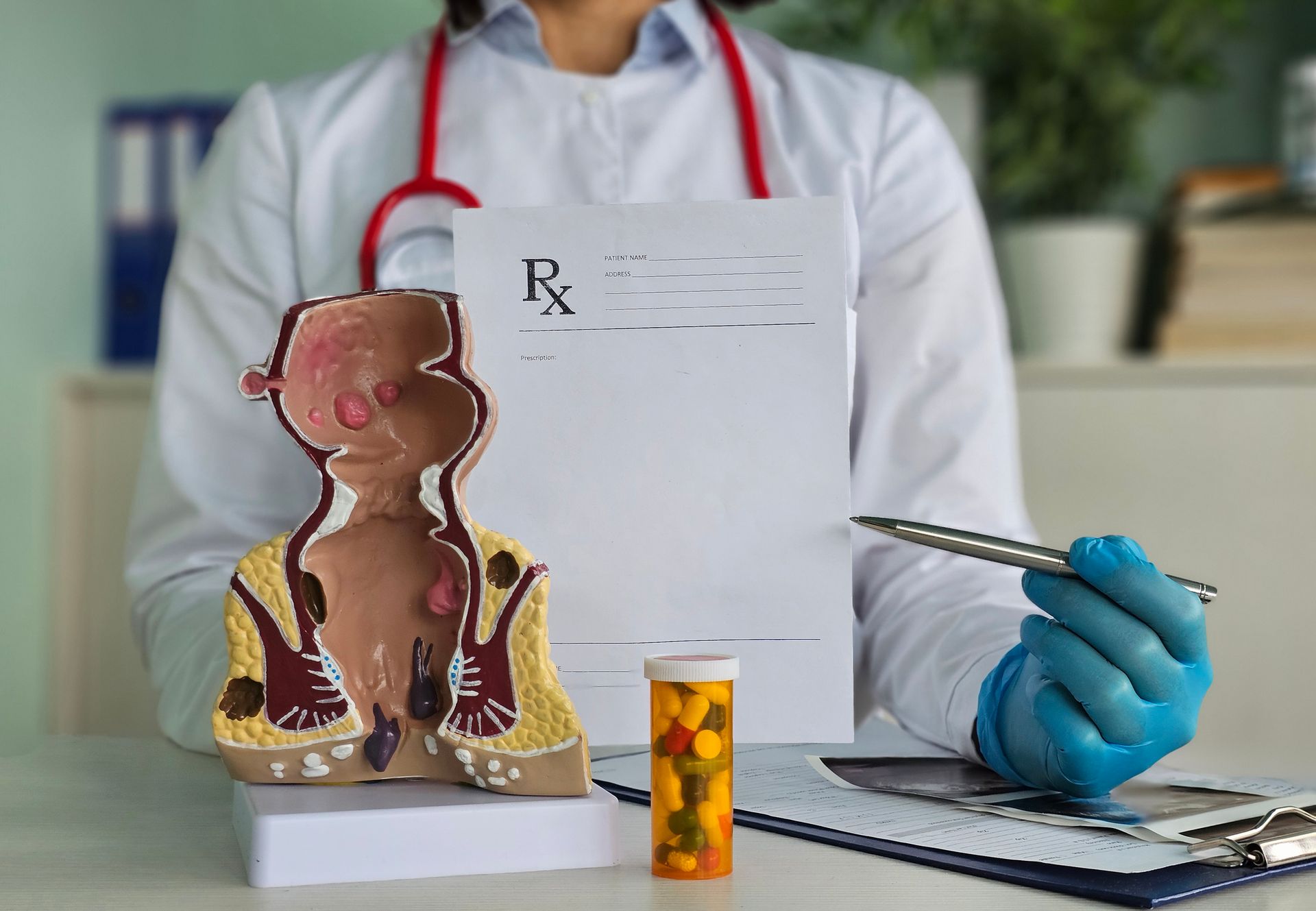 Doctor proctologist holding blisters with pills and anatomical model of rectum.