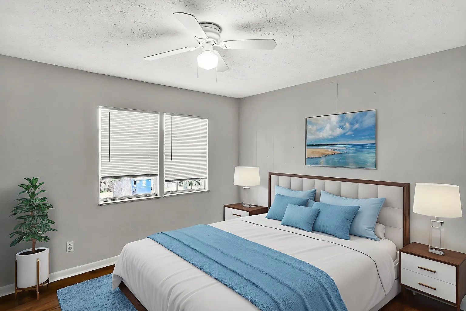 Bedroom with bed, blue accents, artwork, two nightstands with lamps, and a window.