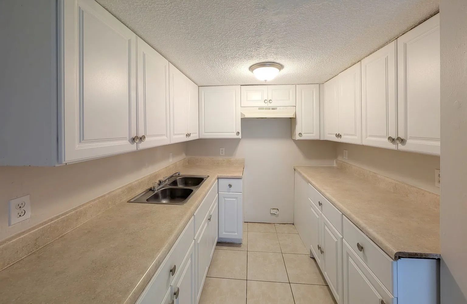 White kitchen with cabinets, countertops, and a sink.