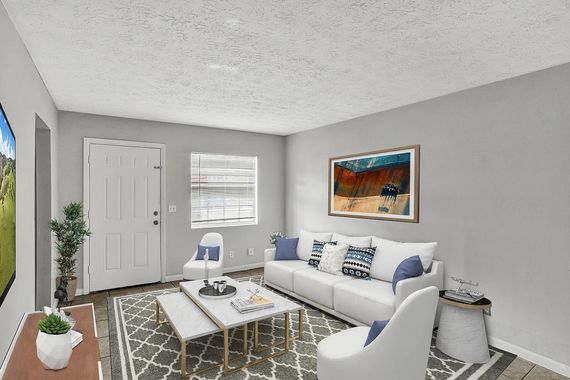 Living room with white sofa, blue accents, artwork, and coffee table.
