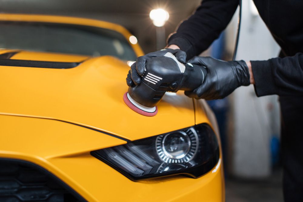 A person is polishing a yellow car with a machine — Shane’s Car Detailing & Office Cleaning in Armidale, NSW