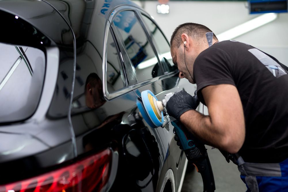 A Man is Polishing a Black Car With a Machine — Shane’s Car Detailing & Office Cleaning in Barraba, NSW