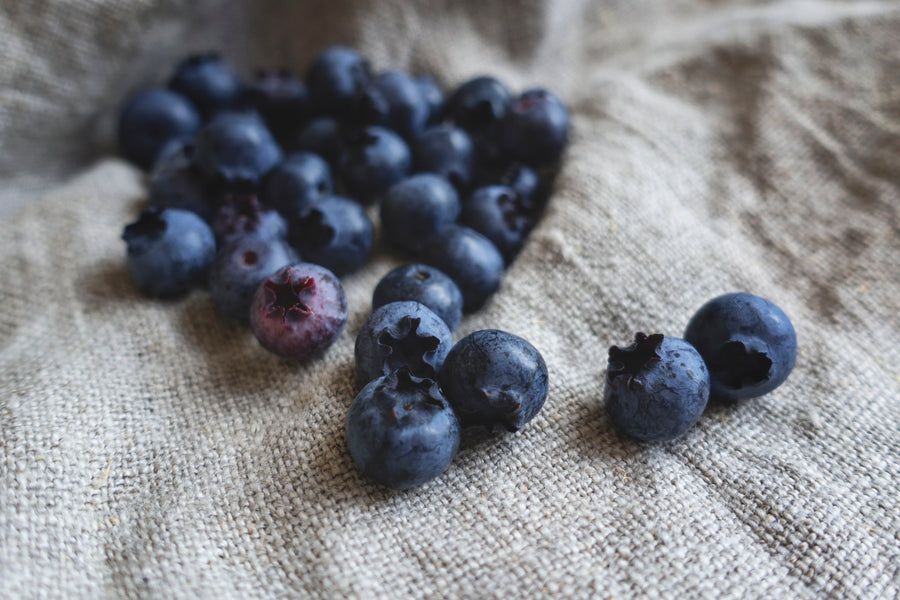A bunch of blueberries are sitting on a cloth on a table.