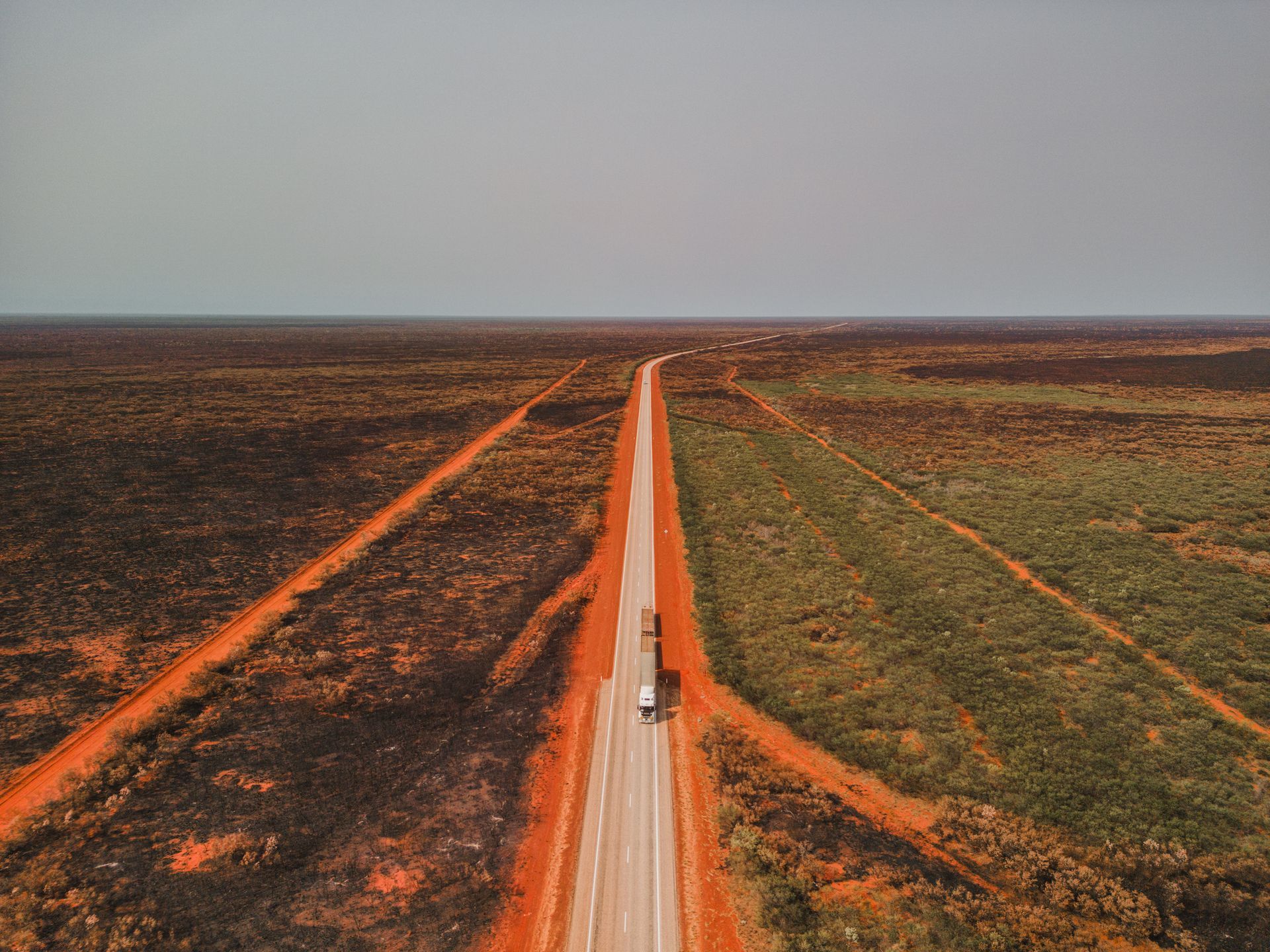 An aerial view of a truck driving down a dirt road in the desert.