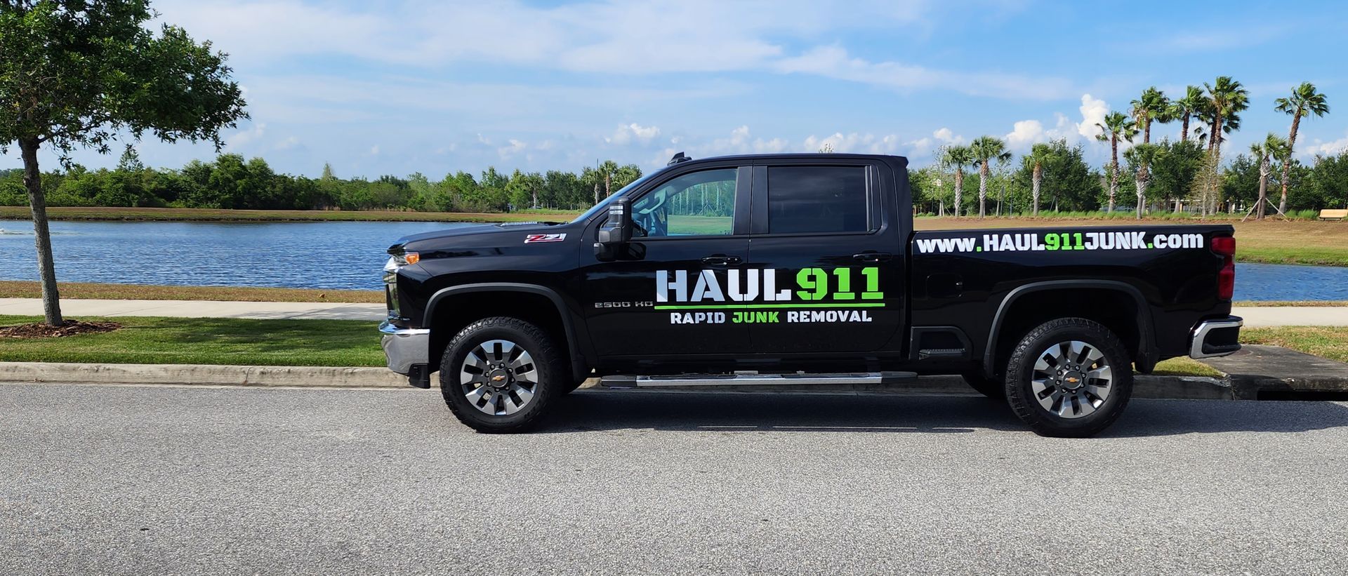 A black pickup truck parked by a lake, featuring the company logo 